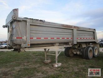 A dump truck is parked in a grassy field.