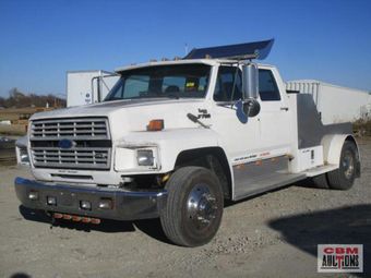 A white ford truck is parked in a gravel lot