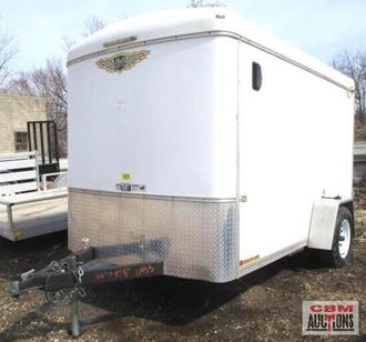 A white trailer is parked next to a cbm auction sign