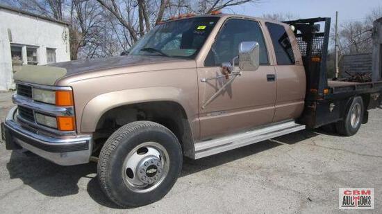 A brown truck with a flatbed is parked in a parking lot.