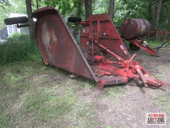 A red tractor is sitting in the grass next to a trailer.