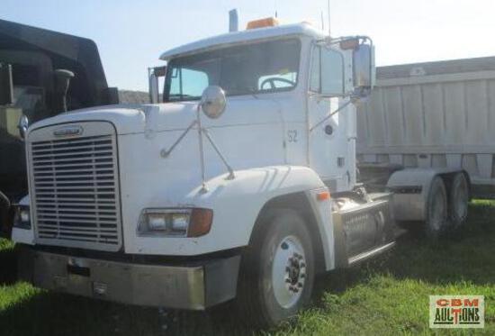 A white semi truck is parked in a grassy field