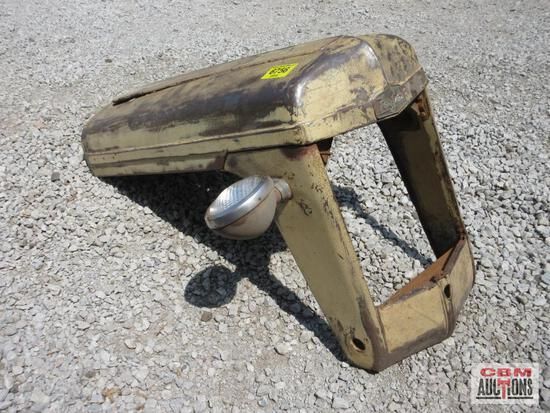 A hood with a light attached to it is sitting on a gravel road.