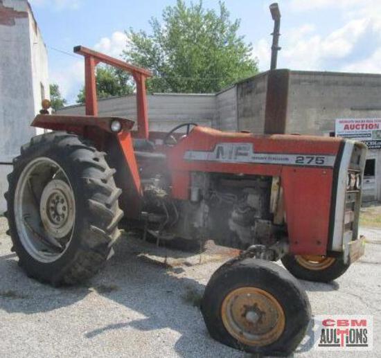 A red tractor is parked in front of a cbm auction