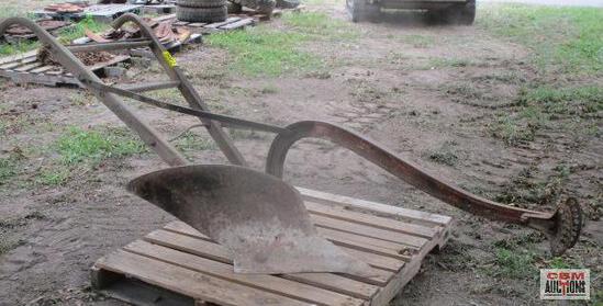 An old plow is sitting on top of a wooden pallet.