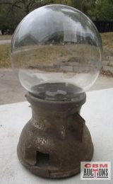 A gumball machine with a clear glass ball inside of it