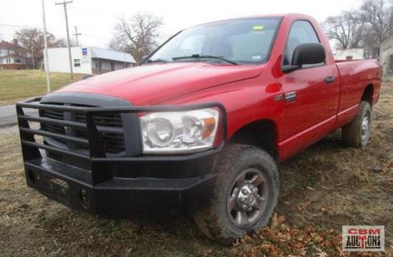 A red truck with a black bumper is parked in a field.