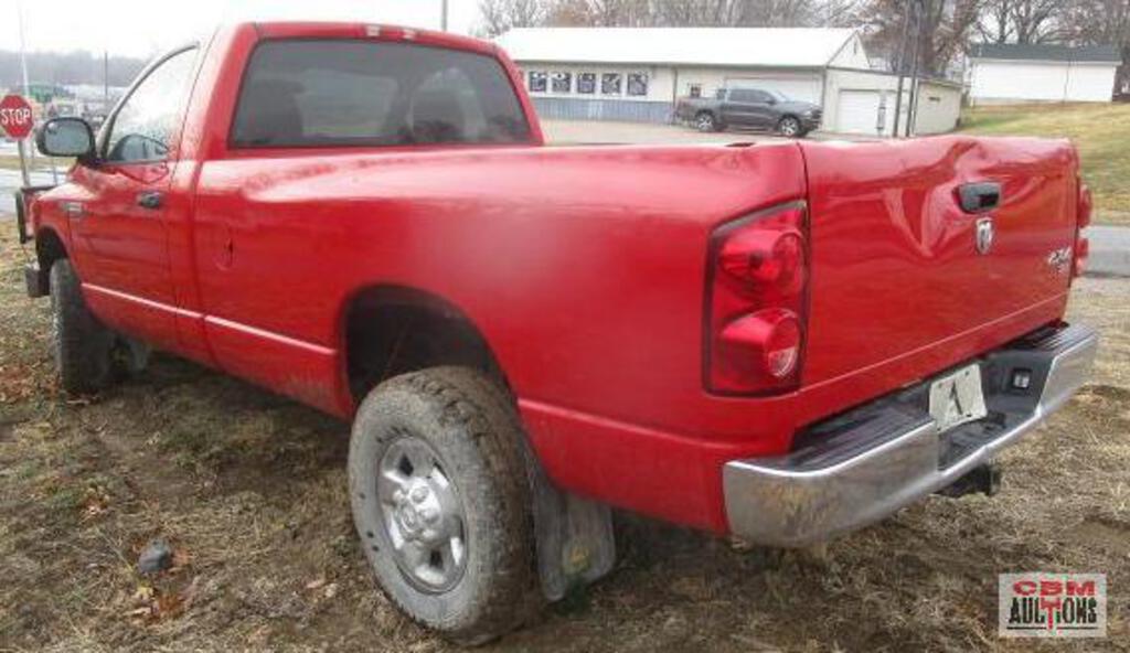 A red dodge ram truck is parked in a dirt field.