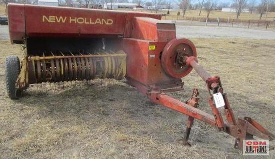 A new holland hay baler is sitting in the grass.