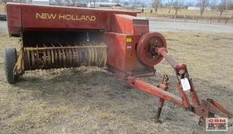A new holland hay baler is sitting in the grass.