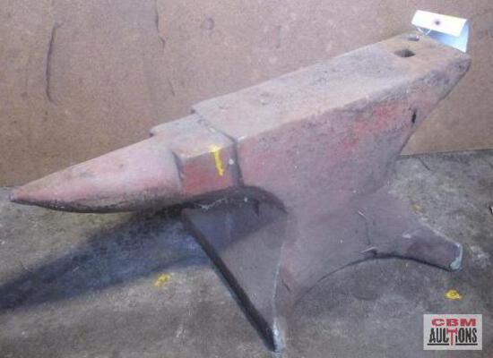 A large anvil is sitting in front of a com auction sign
