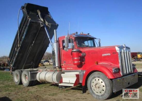 A red dump truck is parked in a dirt field