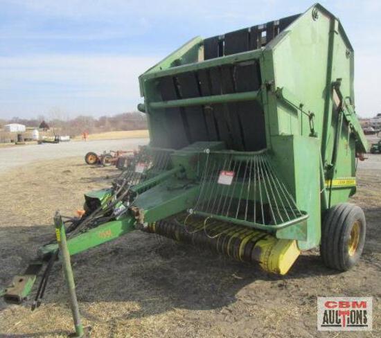 A john deere hay baler is sitting in a field