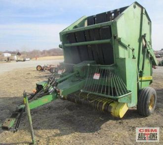 A john deere hay baler is sitting in a field