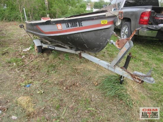 A boat is sitting on a trailer next to a truck.