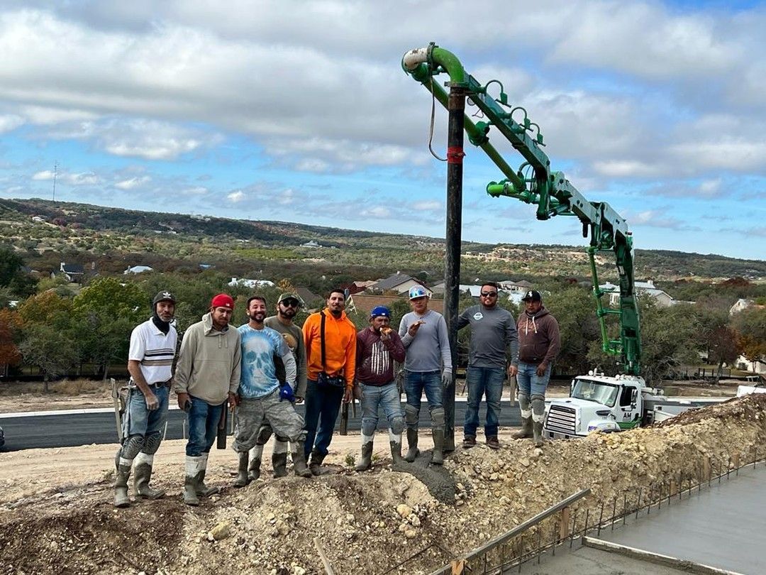 Construction crew poses with a concrete pump truck on a job site.