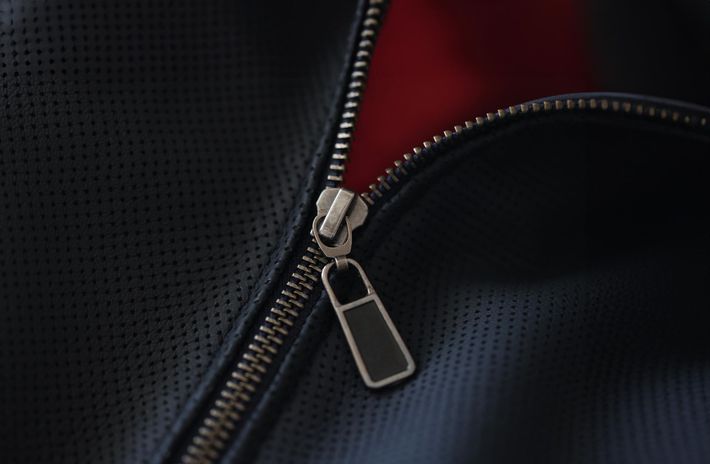A close up of a zipper on a black leather jacket.