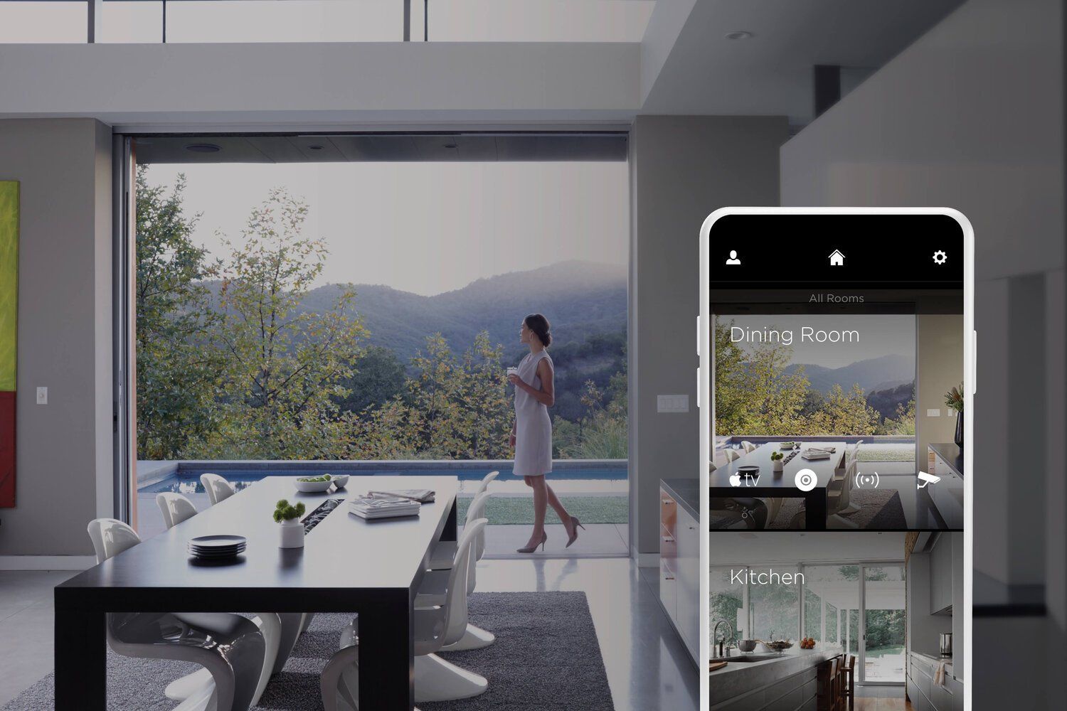 Modern living room with a woman by a large window overlooking mountains, and a smartphone showing home-view camera feeds