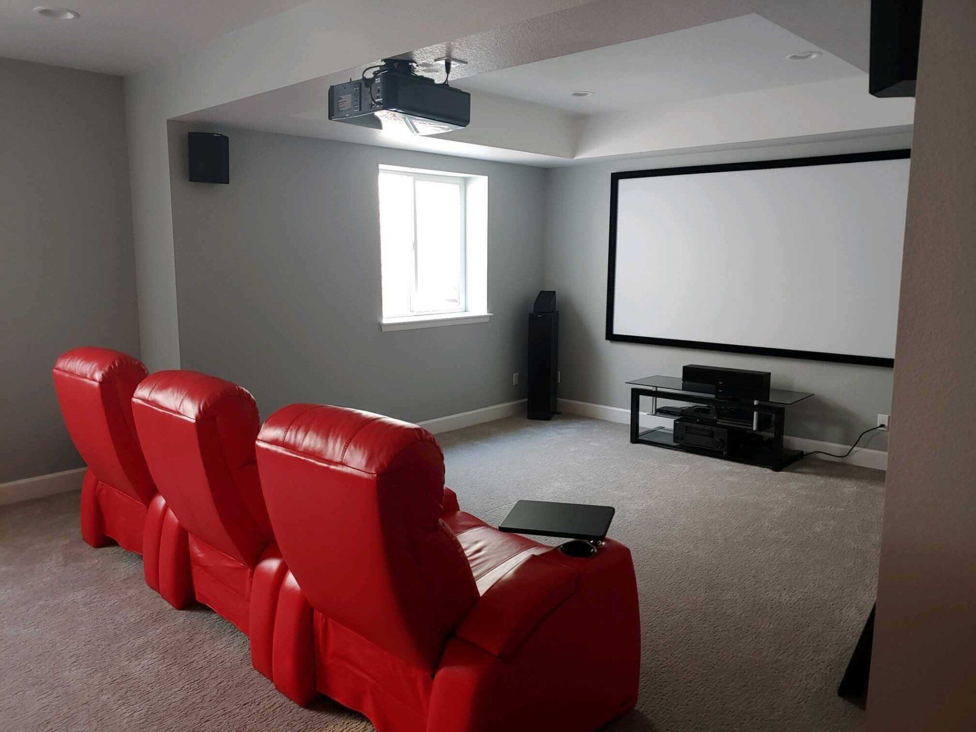 Home theater room with red reclining seats, projector, and large screen