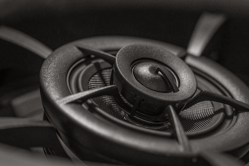 Close-up of a black speaker grille with concentric rings and metal mesh detail