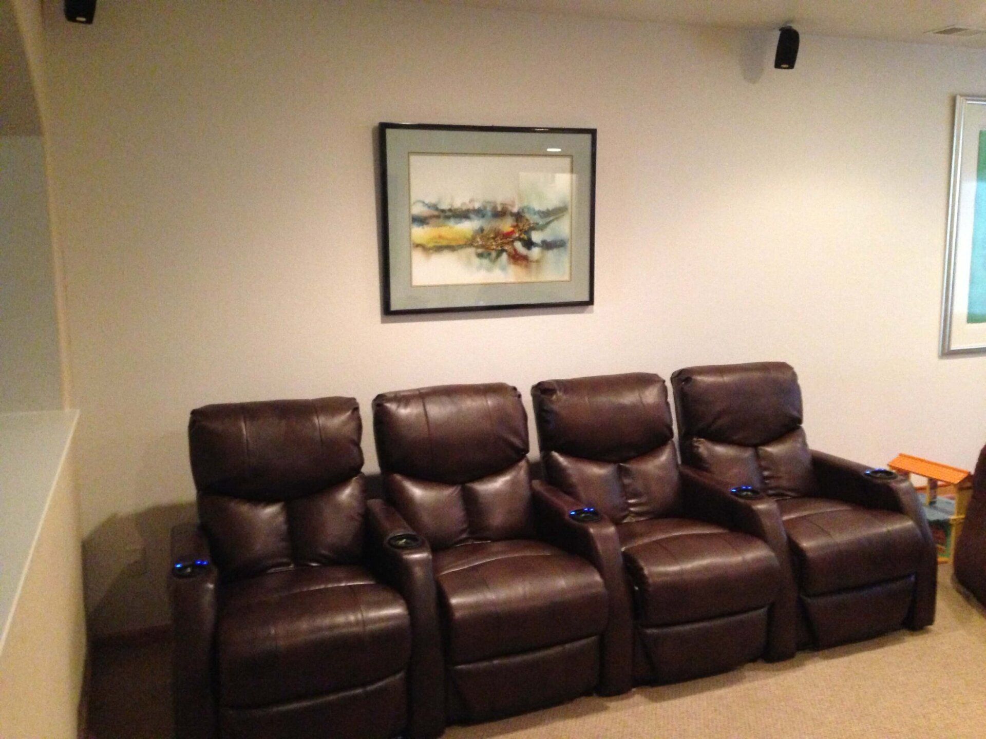 Leather recliner sofa in a living room with framed wall art and wall sconces.