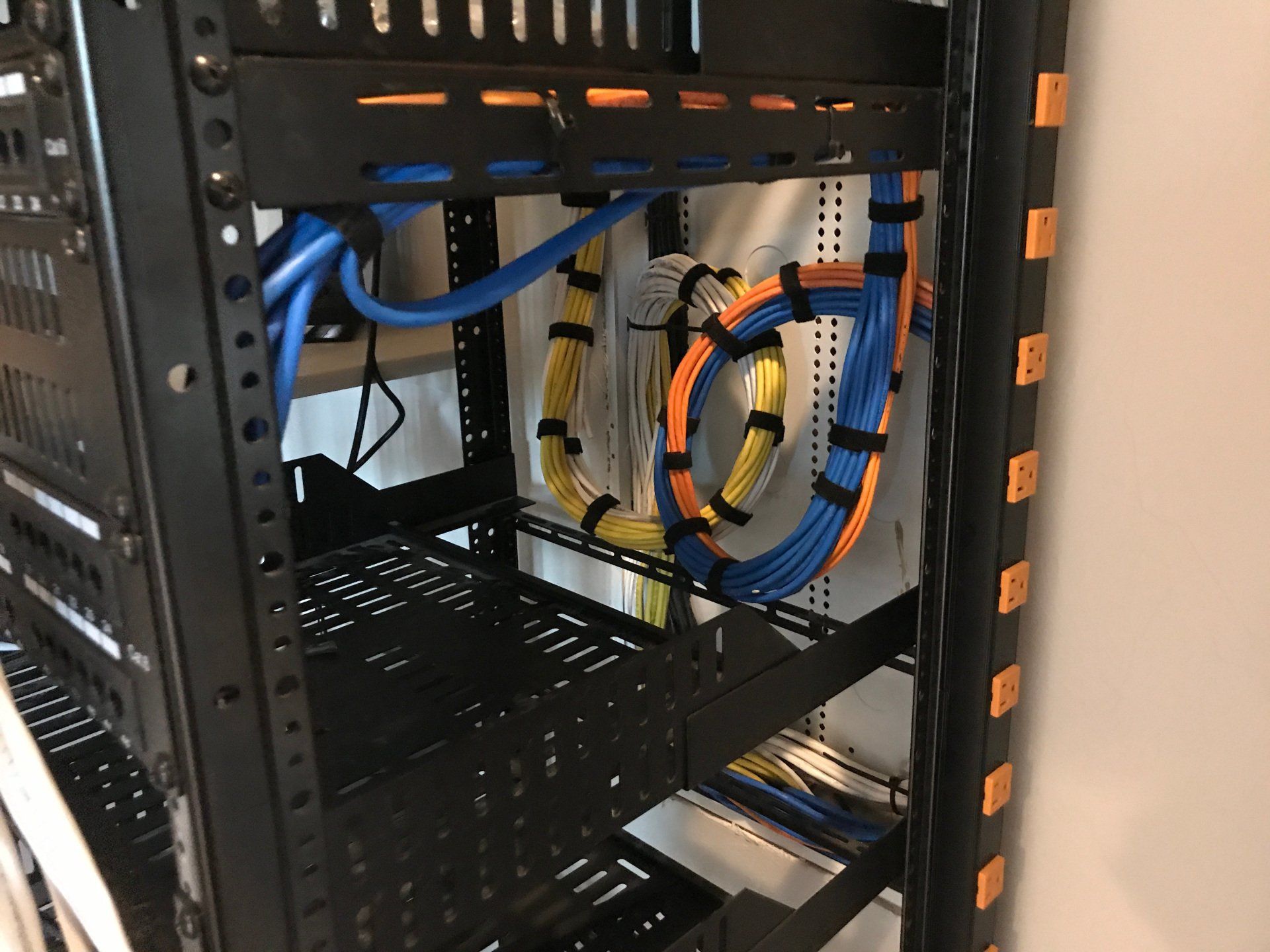 Server rack with blue and yellow network cables and empty shelves in a data room