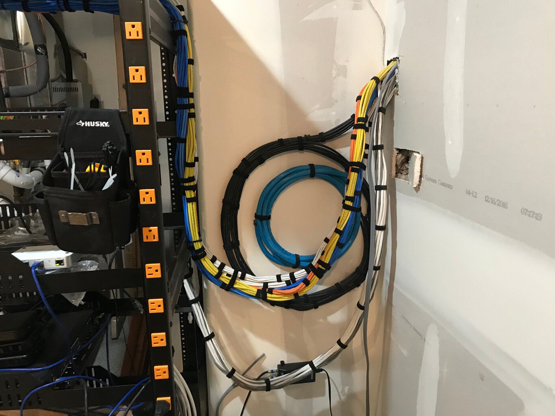 Coiled blue cable and yellow-black wiring mounted on a wall in a utility closet