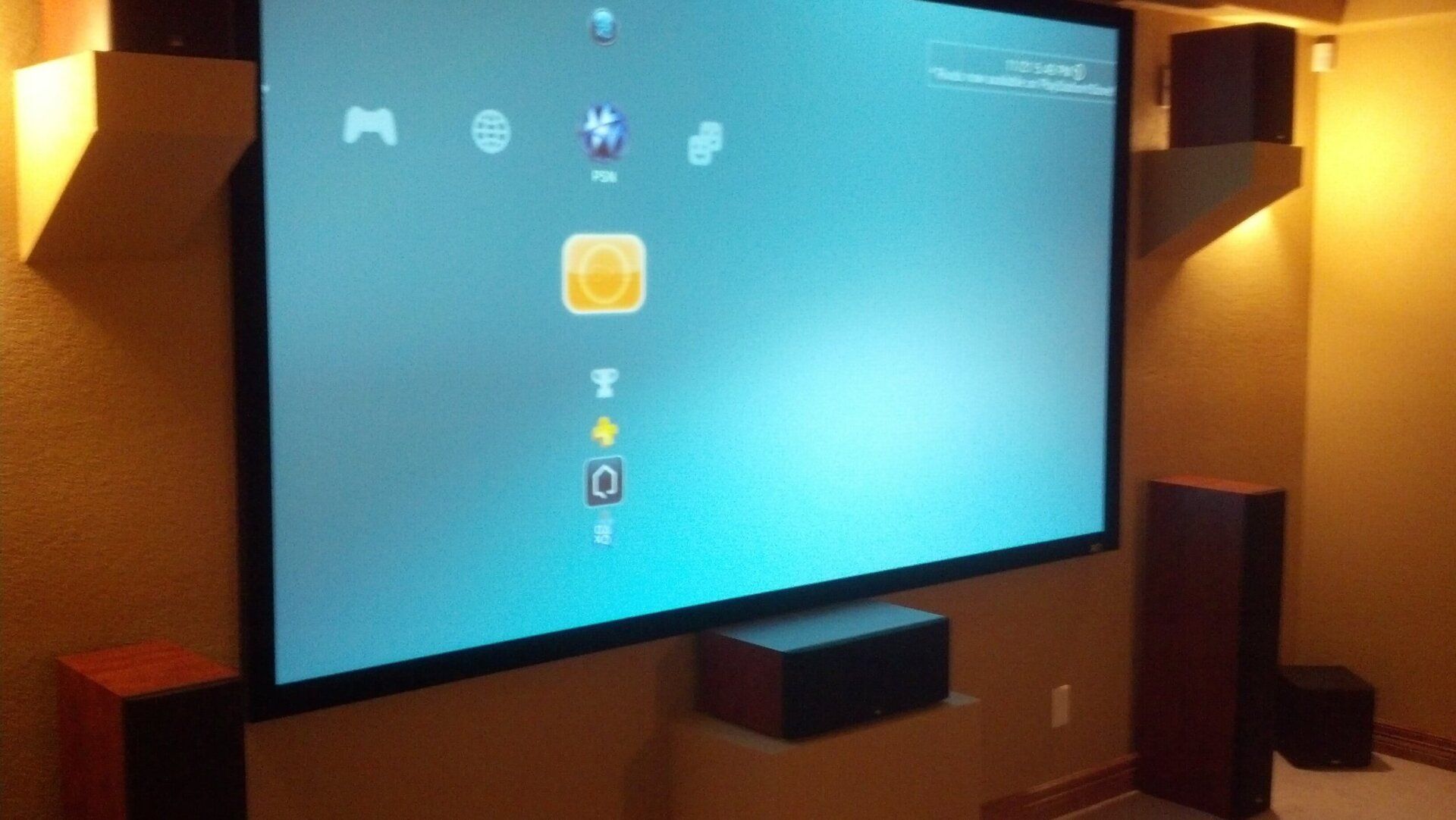 Large wall-mounted screen displaying a game menu in a dim, warm-lit room