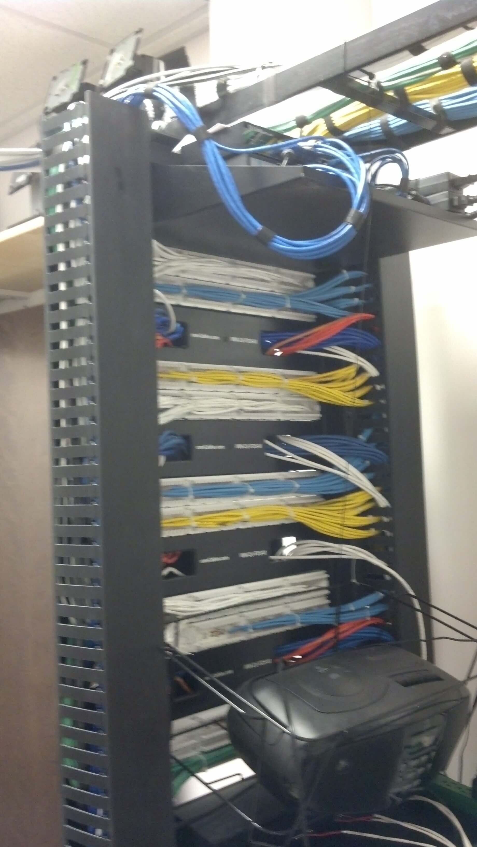Network server rack with bundled blue, yellow, and black cables in a data room