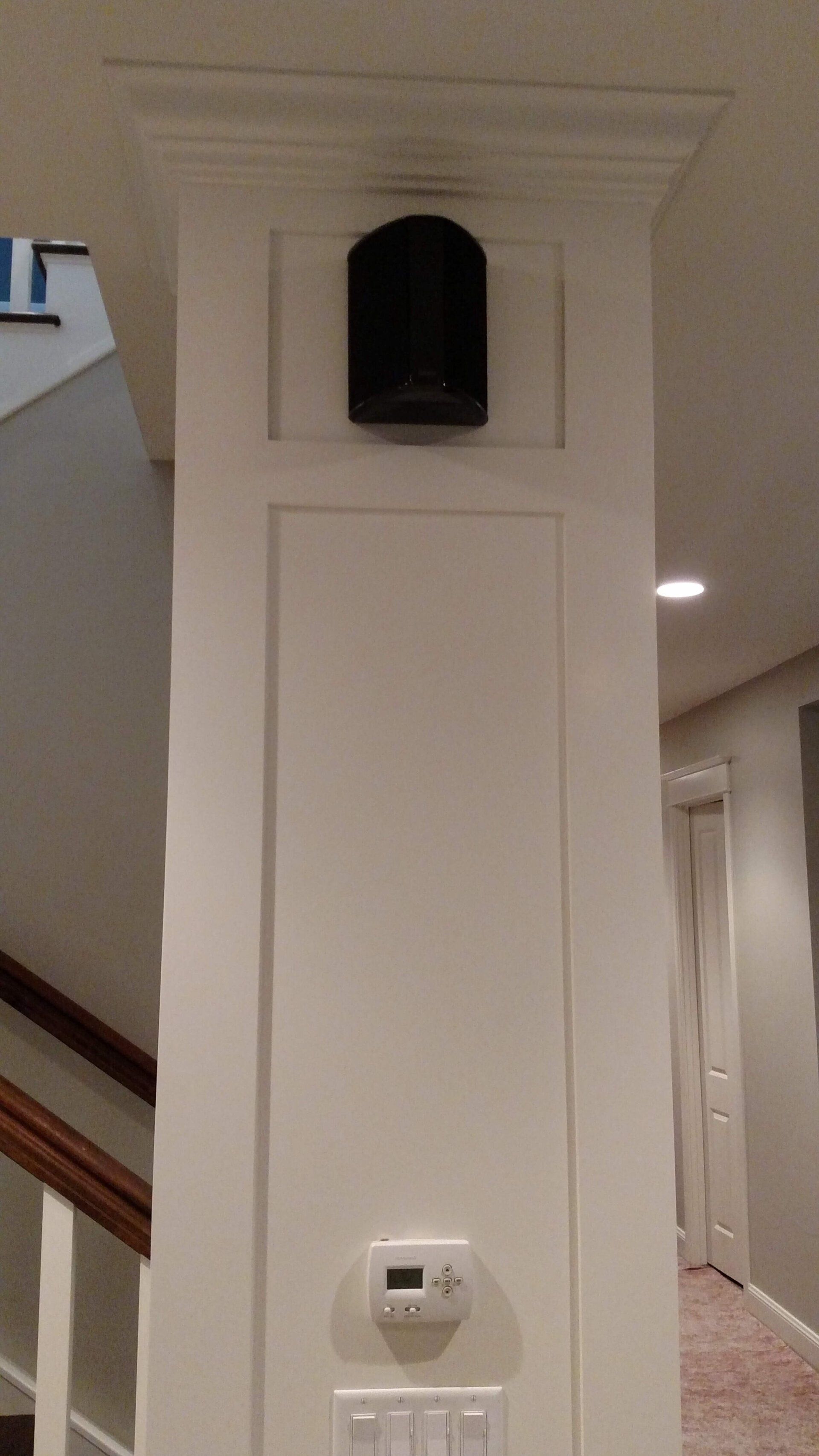 White hallway column with a black wall speaker and a small thermostat near the base.