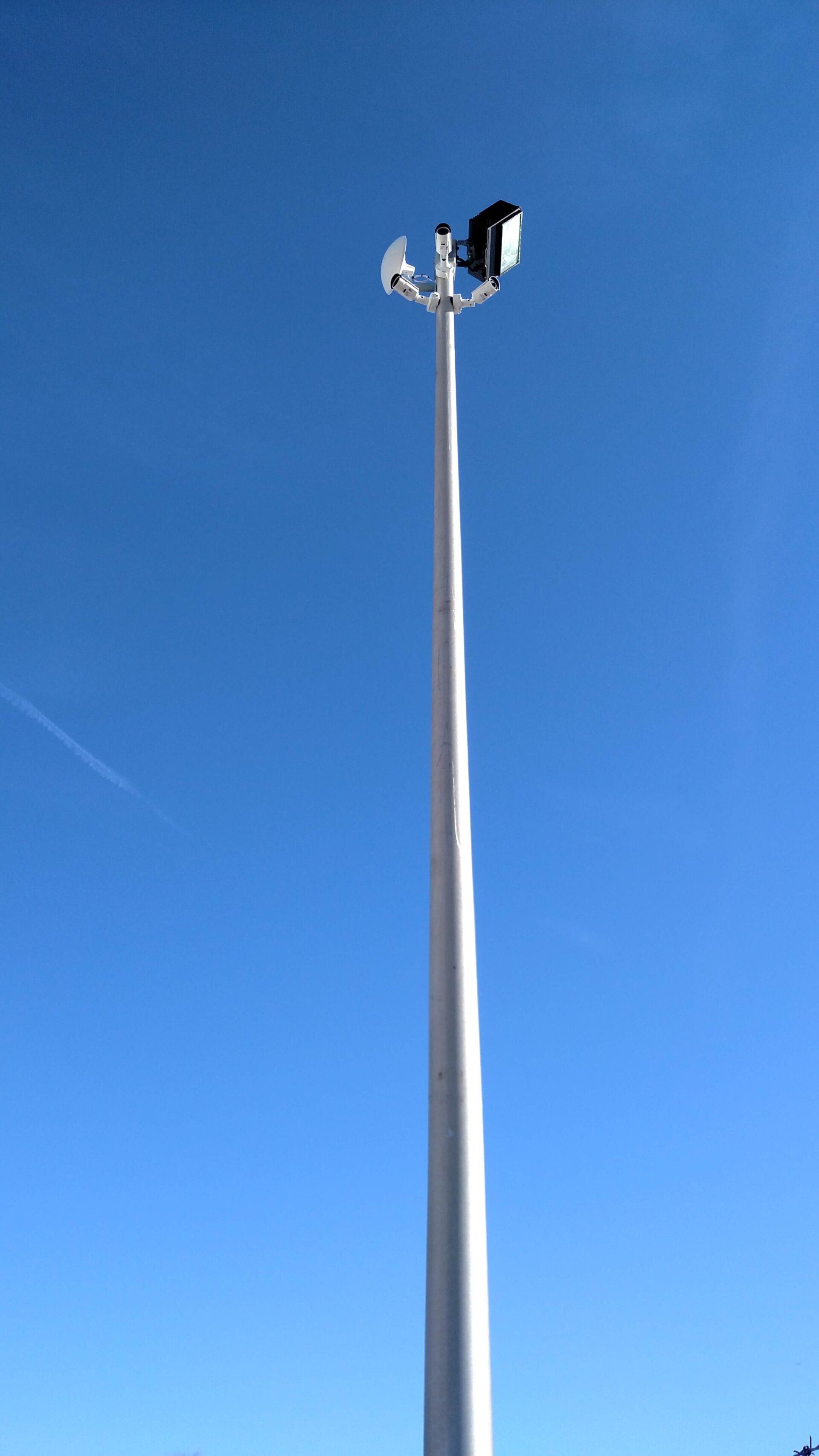 Tall stadium light pole against a clear blue sky