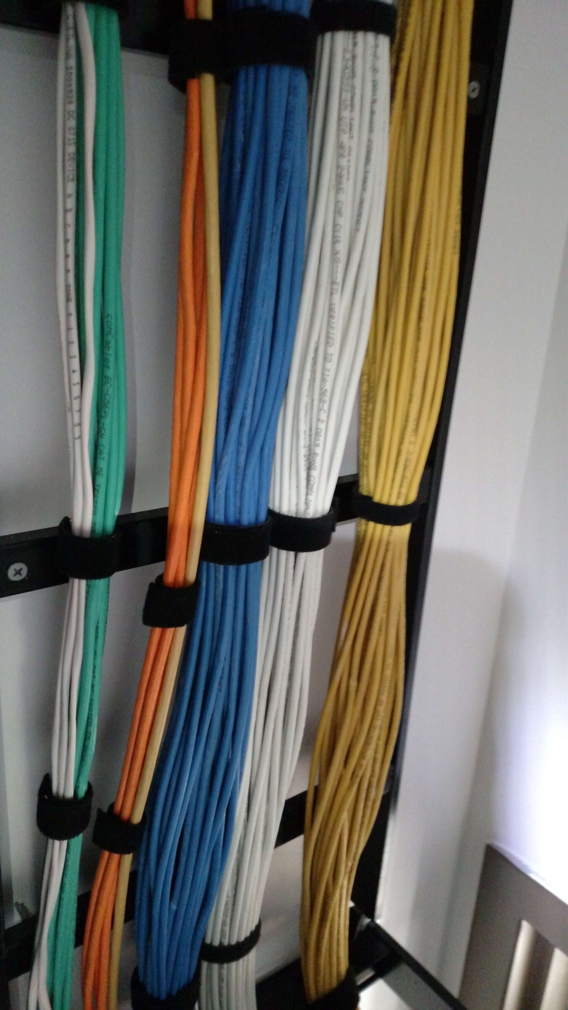 Bundled color-coded cables secured vertically against a wall with black straps