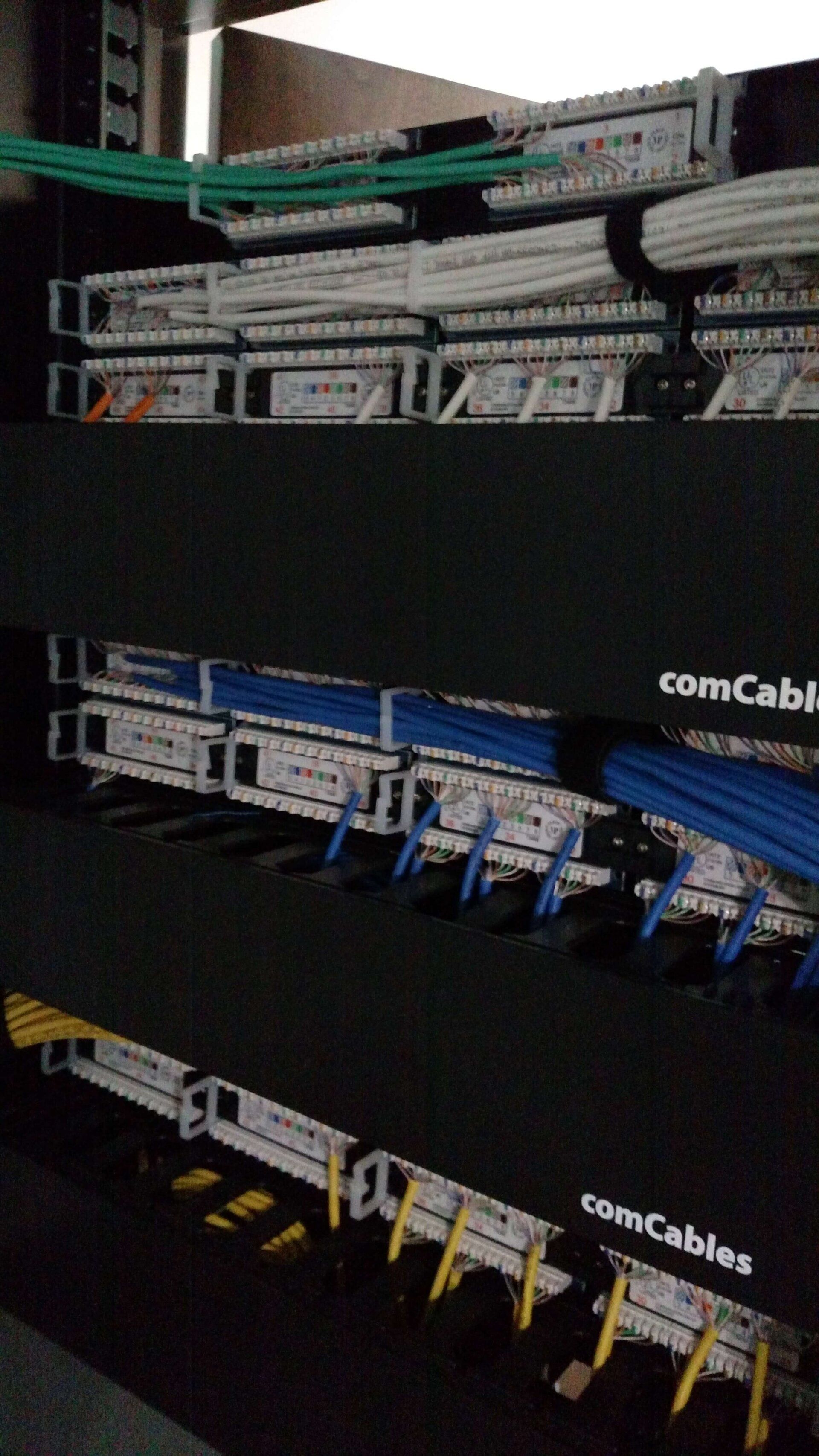 Close-up of a network patch panel with bundled cables and color-coded Ethernet connections in a rack