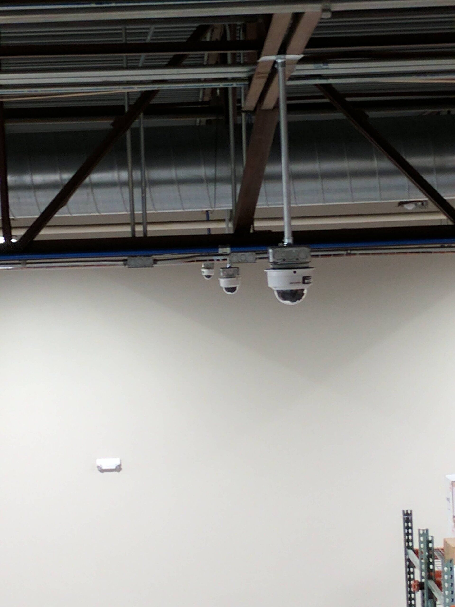 Empty industrial interior with exposed ceiling beams and a white wall under hanging fixtures