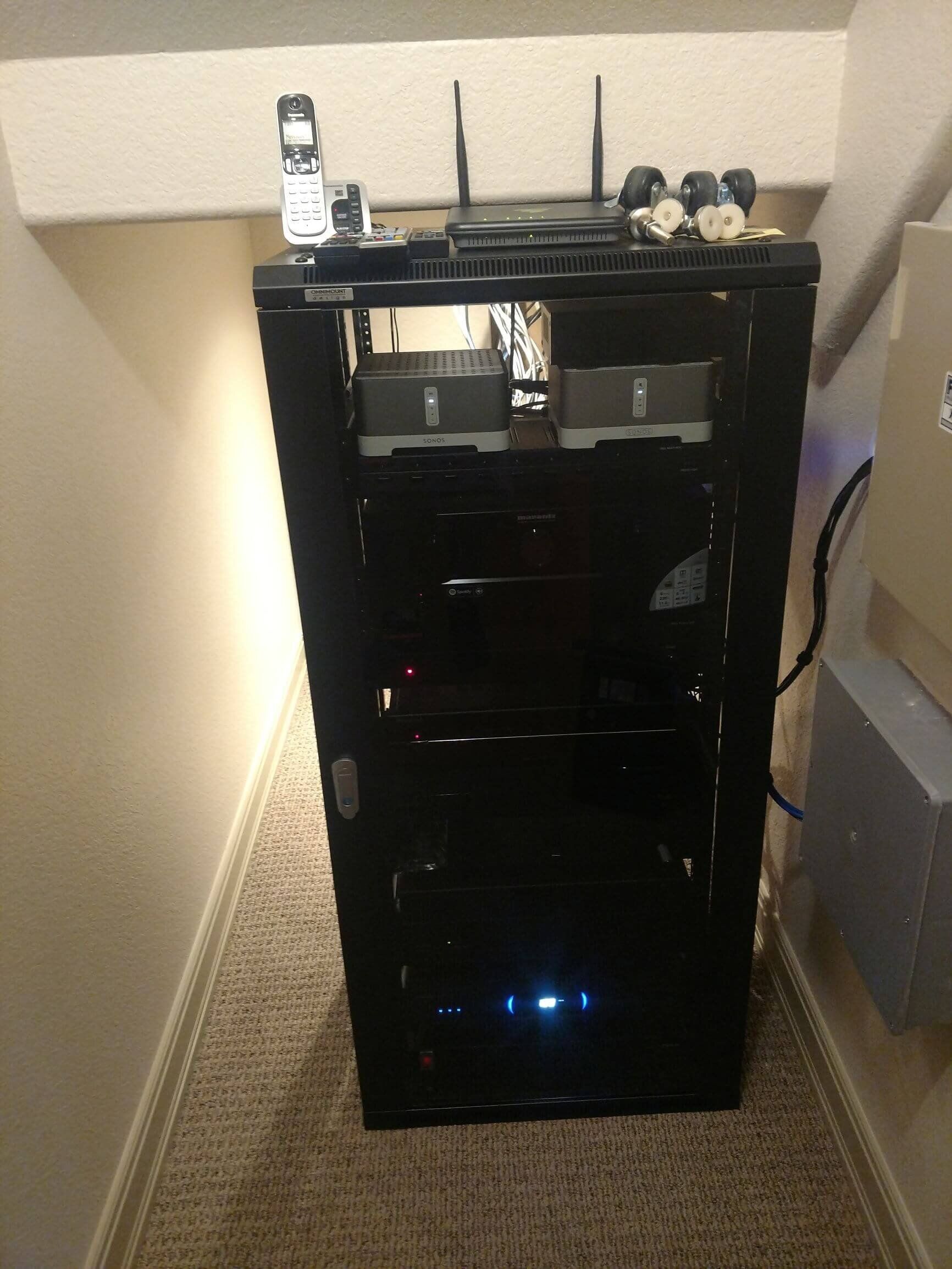Black equipment cabinet with lit indicators, placed in a narrow hallway corner.