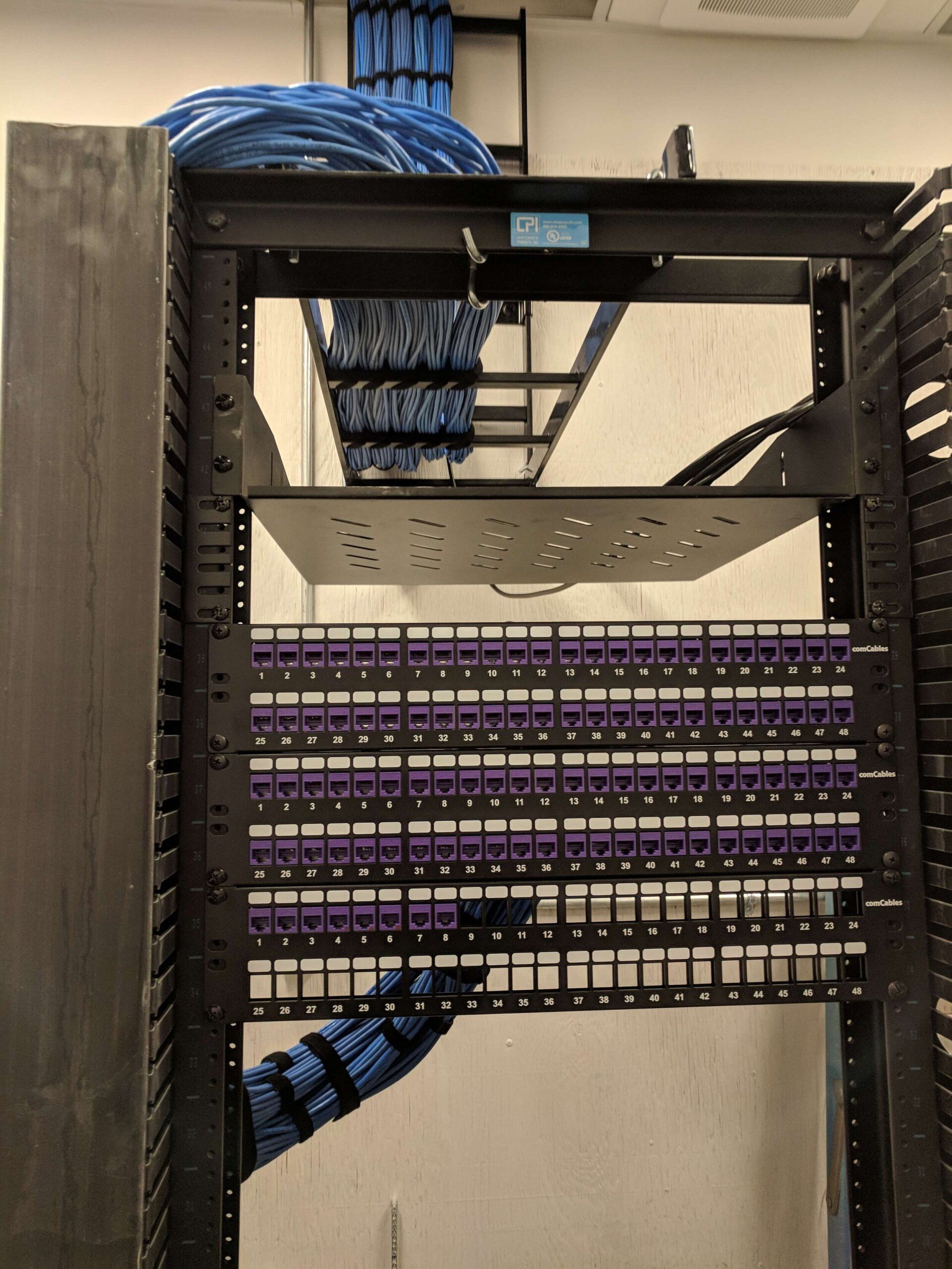 Server rack with network patch panels and blue cables in a data closet