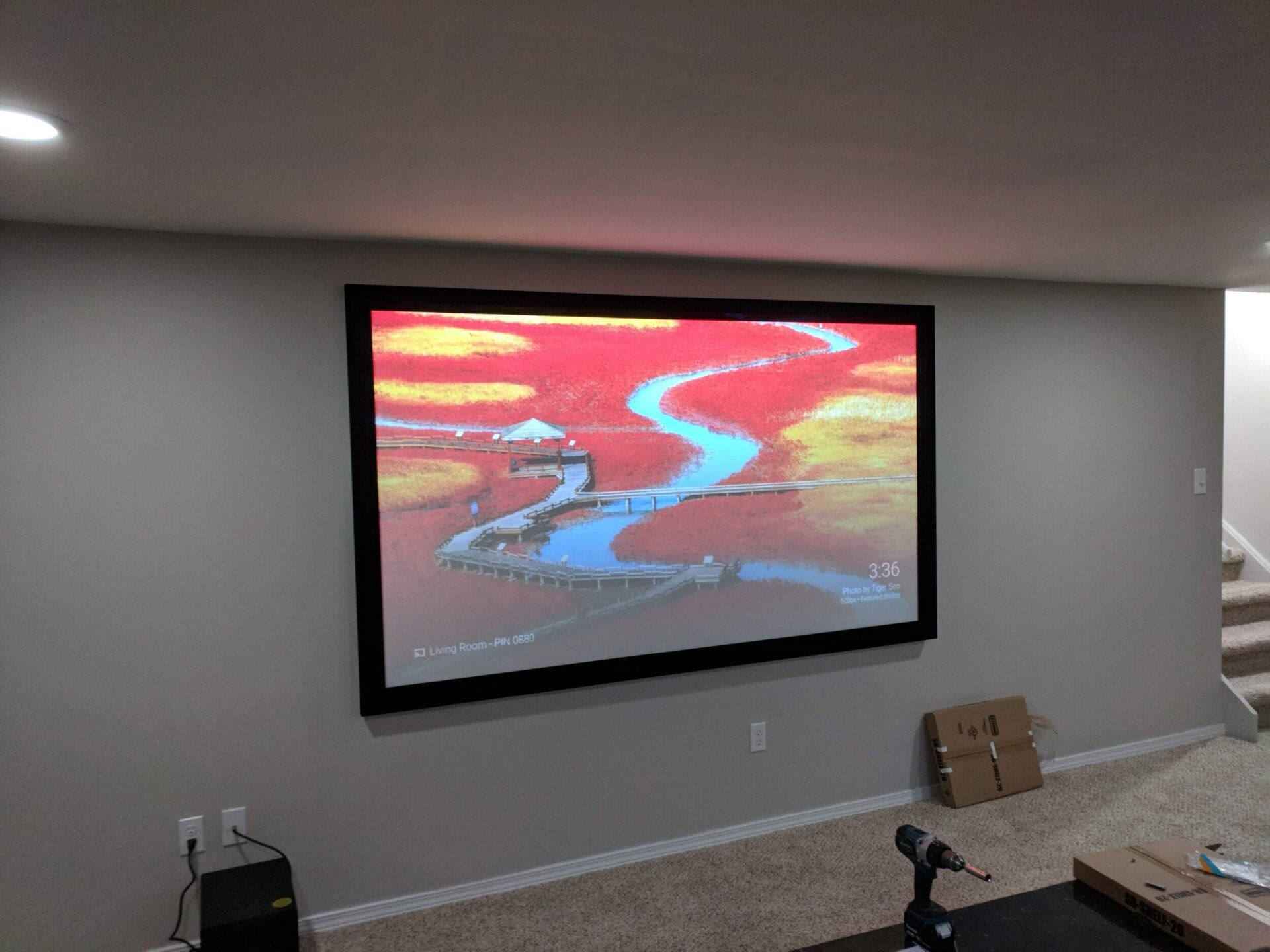 Projected colorful river landscape on a wall-mounted screen in a gray room.