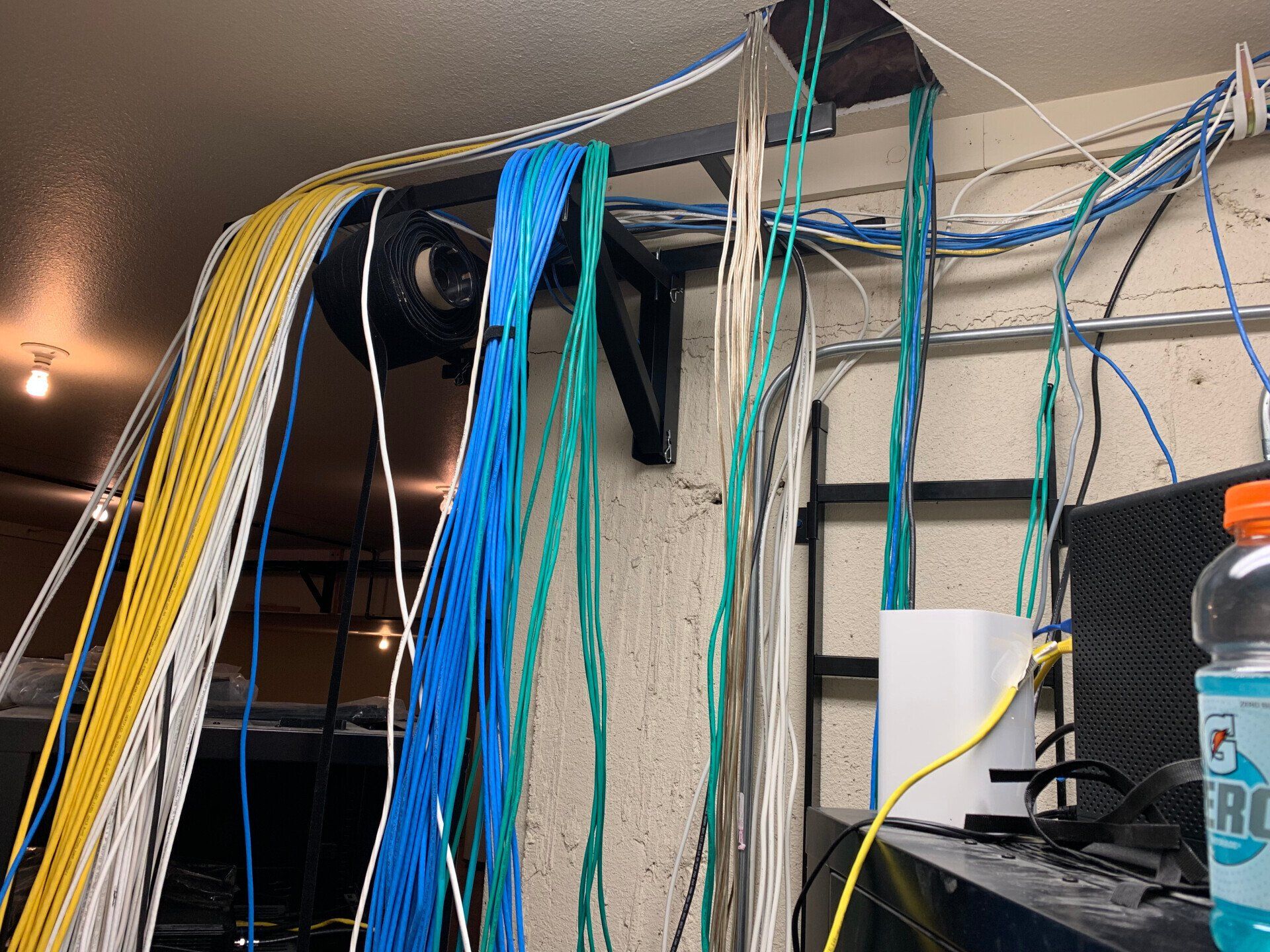 Color-coded network cables bundled in a server room, hanging over equipment racks.