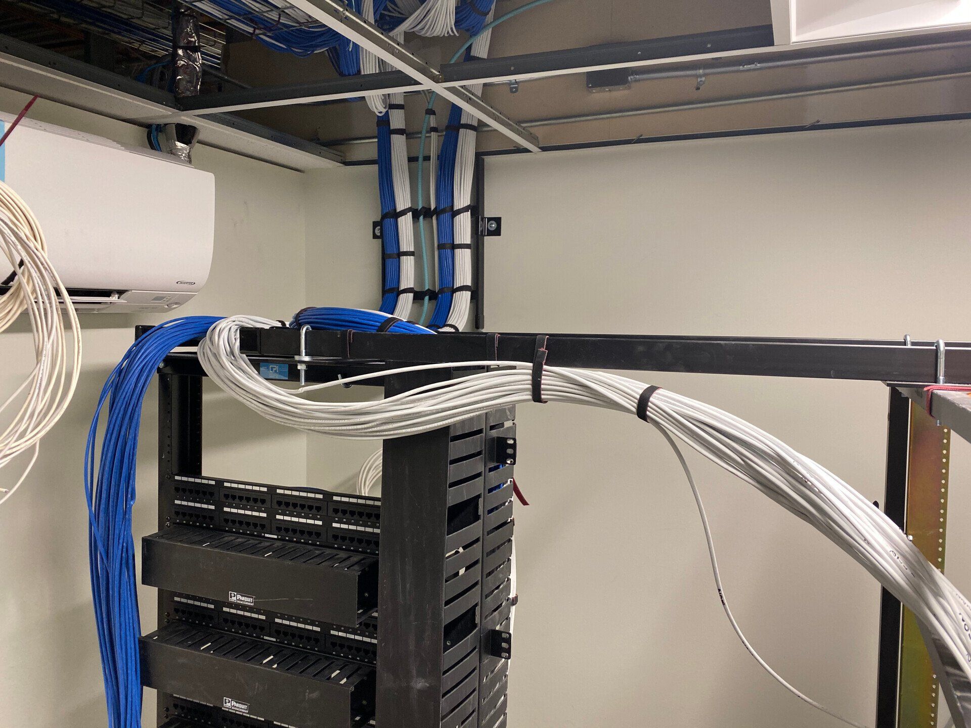 Cables routed through a server rack in a data center, with blue and white cables overhead