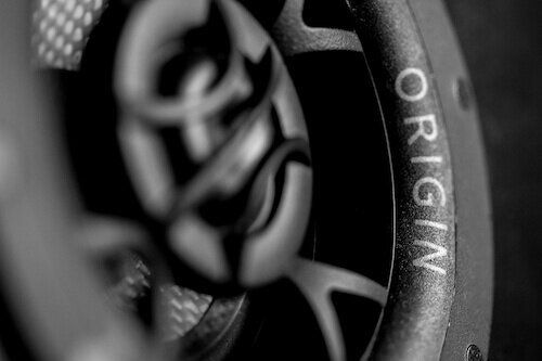 Close-up of a black speaker grille with the word “ORIGIN” on the rim