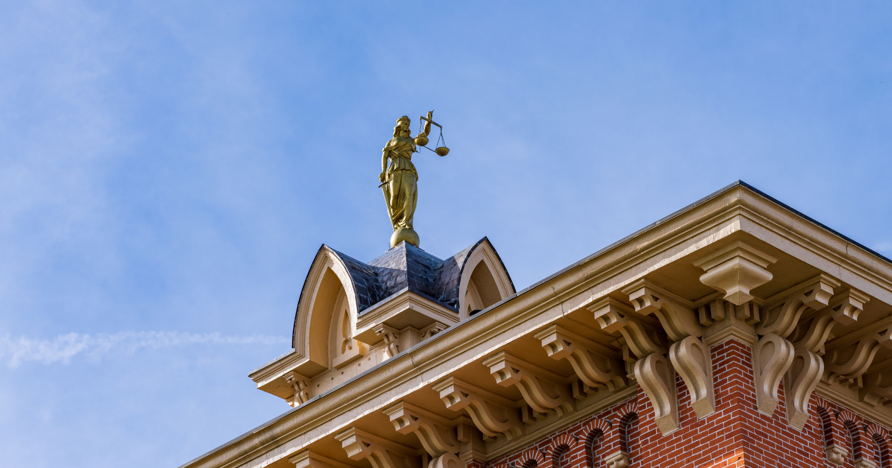 Golden statue atop a building’s ornate roof against a blue sky