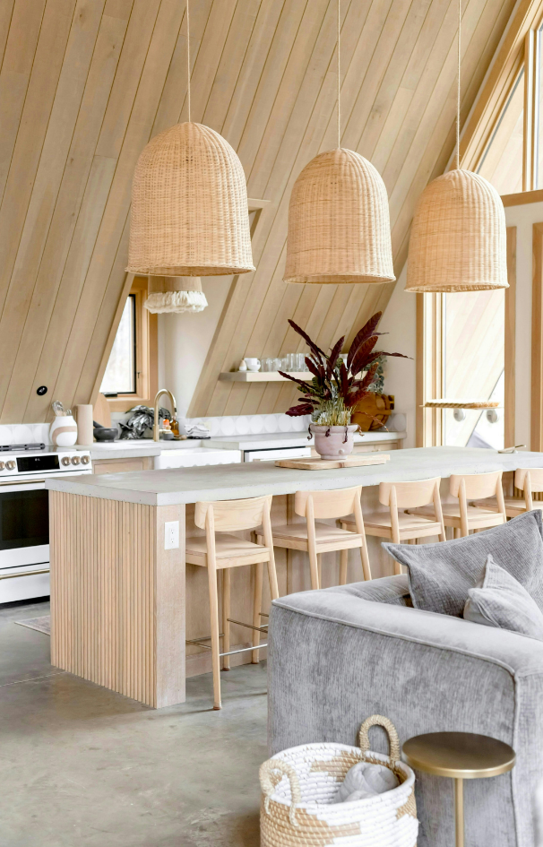 Modern light wood kitchen with woven pendant lights and a gray sofa in the foreground