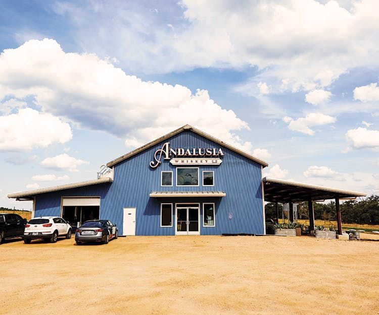 Blue barn-style roadside building with parked cars under a cloudy sky