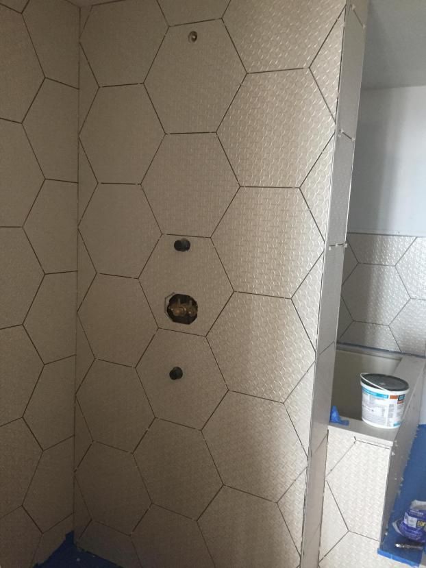 Bathroom with hexagon tile walls, plumbing fixtures visible.