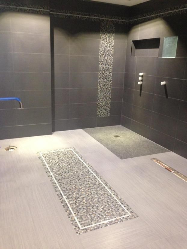 Bathroom with gray tile walls, a pebble shower floor, and a long pebble inlay on the floor.