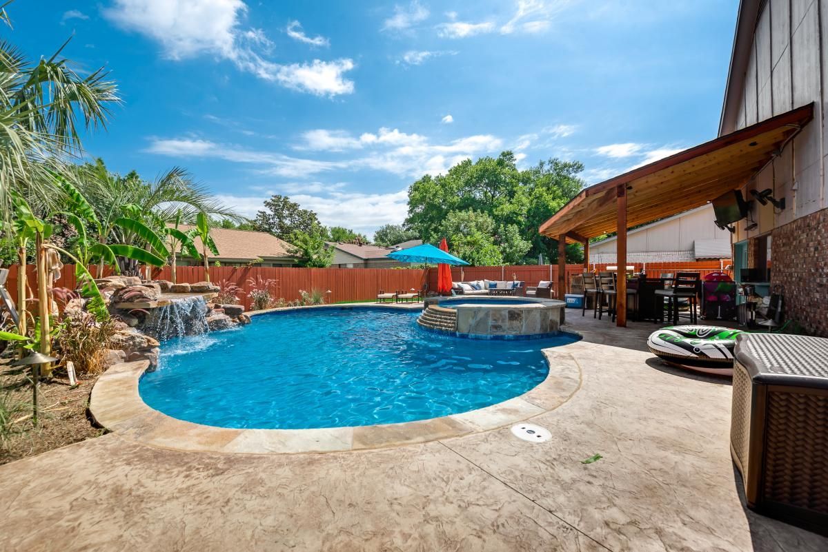 Backyard resort-style pool with lounge chairs, patio seating, and clear blue sky