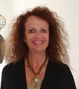 Een lachende vrouw met krullend kastanjebruin haar, gekleed in een zwarte top