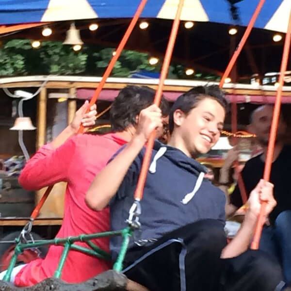 Mensen lachen in een draaiende kermisattractie met rode veiligheidsbeugels.