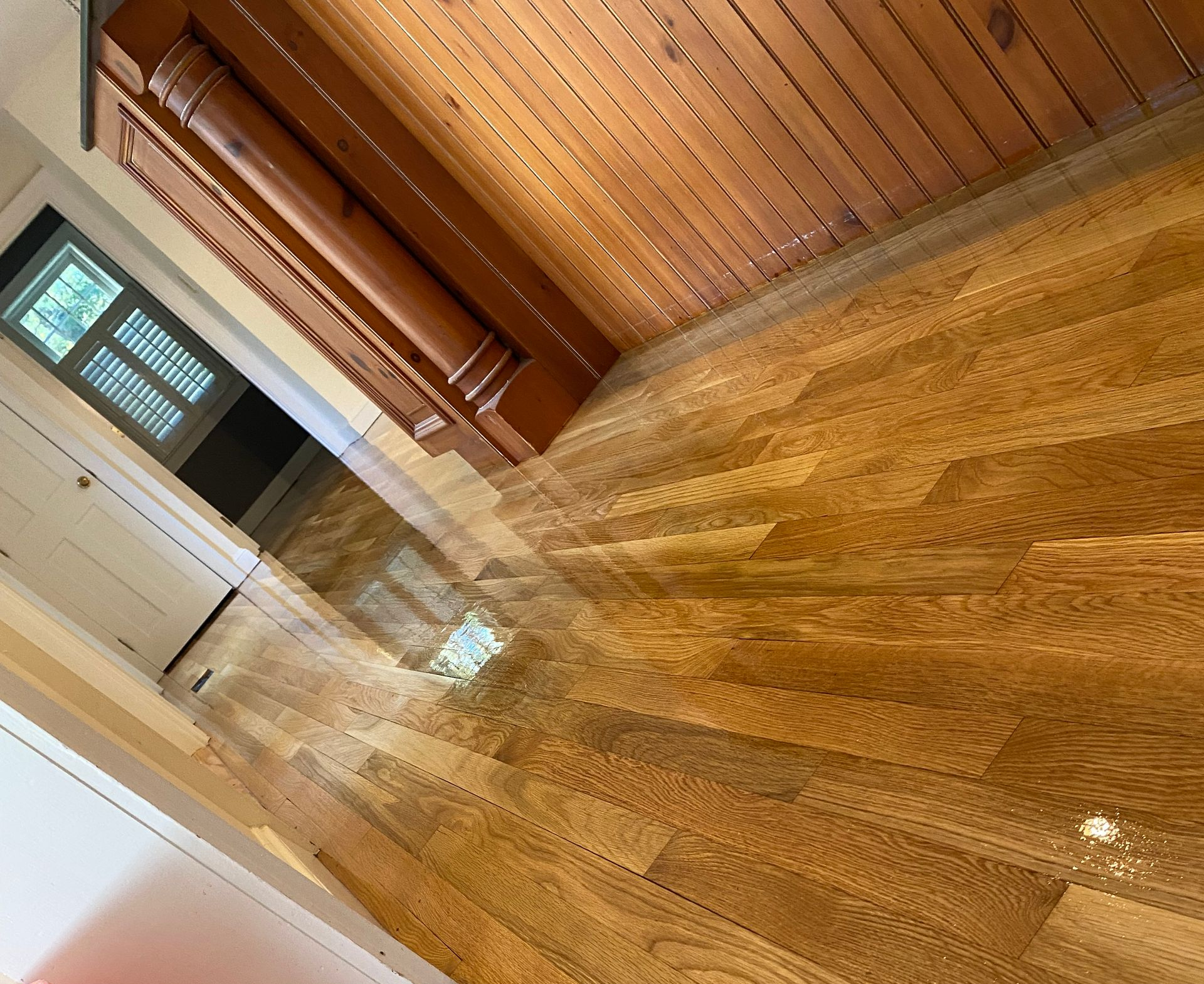 White couch positioned near a black mat on a hardwood floor.
