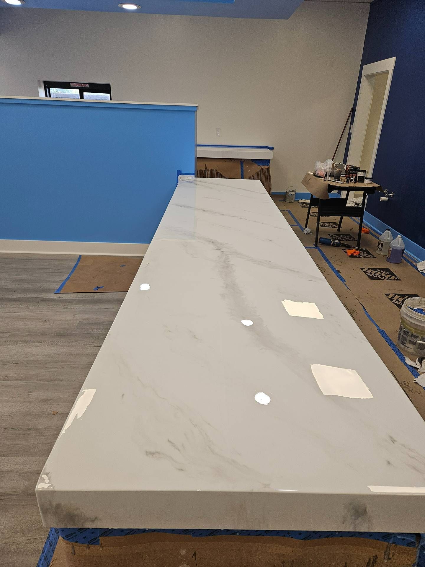 Empty room with a long white worktable, blue partitions, and scattered tools on the right.